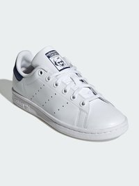 White leather sneaker with a rounded toe, lace-up design, perforated detailing on the sides, and a blue accent at the heel.
