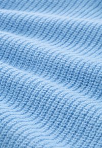 Weiches, blaues Strickgewebe mit einem strukturierten Rippenmuster, das sanfte Wellen auf der Oberfläche erzeugt.