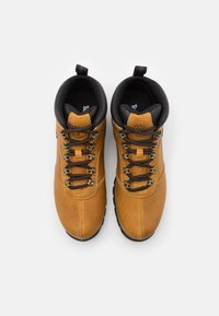 Scarponi da trekking in pelle marrone con accenti neri, occhielli in metallo e lacci testurizzati; presentano un collare imbottito e suole in gomma resistenti.
