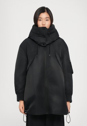 Black puffer jacket with a high collar, zip front, side pockets, and adjustable drawstrings. Features a smooth, matte texture.