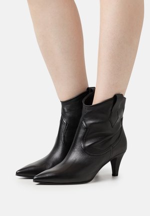 Stivaletti alla caviglia in pelle nera con punta appuntita, caratterizzati da sottili dettagli di cucitura e un tacco leggero, progettati per una silhouette aderente alla caviglia.