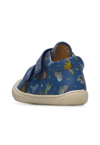 Chaussures en cuir bleu pour tout-petits avec une semelle en caoutchouc beige texturé, arborant des motifs de dinosaures colorés et deux bandes Velcro ajustables.