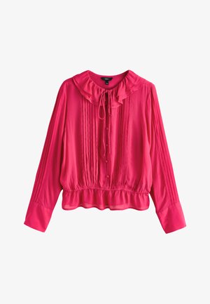 Blouse rose vif à manches longues avec col et ourlet à volants, plis verticaux sur le devant et les manches, boutons recouverts de tissu, et lien noué à l'avant du cou.