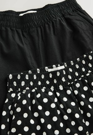 Dva páry čiernych kraťasov s elastickým pásom, jeden jednoliato čierny a druhý čierny s bielymi bodkami, navrstvené na seba s prekrývaním.