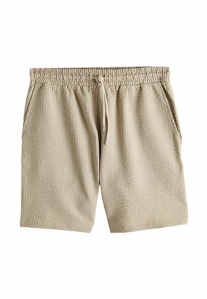 Smėlio spalvos tekstūruoti audinio šortai su elastine juosmens juosta, raišteliu ir šoninėmis kišenėmis, išdėstyti ant baltos fono.