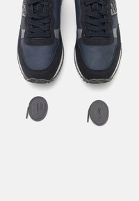 Sneaker blu navy realizzati in materiali scamosciati e in rete, con accenti grigio scuro, lacci e suole in gomma bianca, accompagnati da lacci coordinati.