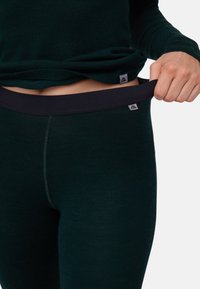 Ciemnozielone legginsy wykonane z miękkiego materiału, z szerokim czarnym elastycznym paskiem w talii. Charakteryzują się delikatnymi przeszyciami i logo na pasku.