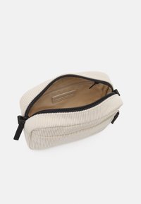 Bag in cosmetica in corduroy di colore bianco sporco con cerniera nera; presenta un compartimento principale e una fodera interna liscia.