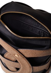Round tote bag featuring a black fabric body with an embossed beige pattern. Gold zipper and inner compartments with textured lining.