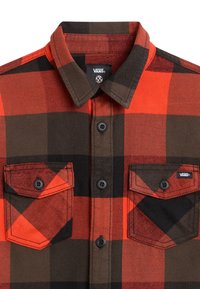 Camicia in flanella con un motivo a quadri rosso e nero, colletto button-down, due taschini sul petto e bottoni scuri, realizzata in un tessuto testurizzato.
