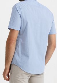 Camicia a maniche corte con bottoni di colore azzurro chiaro con motivo a quadretti, caratterizzata da un orlo dritto e una vestibilità casual. Realizzata in tessuto traspirante.