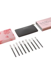 Ti makeupbørster med sorte håndtag arrangeret i en række med en sort lynlåspung og lyserøde blomster- og tekstbokse.