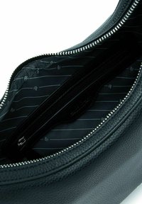 Zwarte leren tas met een textuur in het interieur, voorzien van een ritszak, met een zwart-wit gestreepte voering en zilverkleurige hardware.