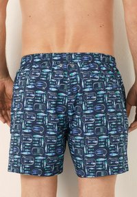 Costum de baie scurt cu un pattern albastru, av�ând un design cu pești și plasă de pescuit. Materialul este ușor, cu un talie elastică. Fără buzunare vizibile.