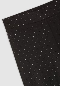 Czarne legginsy z gładkiego materiału, ozdobione powtarzającym się wzorem małych srebrnych ćwieków równomiernie rozmieszczonych na powierzchni.