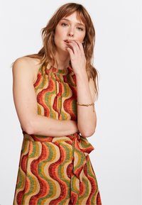 Bunt gekleidetes Kleid mit einem wellenförmigen Muster in Rot, Grün und Gold. Ärmelloses Design mit einer gebundenen Taille, strukturiertem Stoff und rundem Ausschnitt.