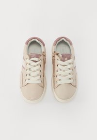 Baskets beiges avec une texture en cuir lisse, lacets blancs, accents roses et un poignet pailleté. Présente une fermeture éclair sur un côté.