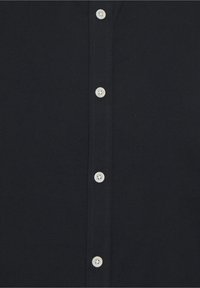 Camisa de botones azul marino con botones blancos, una textura suave y un cuello clásico. La tela parece ligera y duradera.