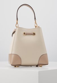Sac seau en cuir crème et beige avec quincaillerie dorée, surface texturée, coins arrondis et une courte poignée. Design classique avec des accents.