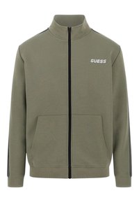 Sudadera verde oliva con cremallera, hecha de mezcla de algodón. Cuenta con un cuello alzado, dos bolsillos frontales y franjas negras contrastantes en las mangas.