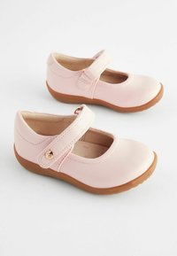 Roze usnjene Mary Jane čevlje z zaobljenim prstom in nastavljivim trakom. Imajo bež gumijast podplat in majhen okrasni detalj na traku.