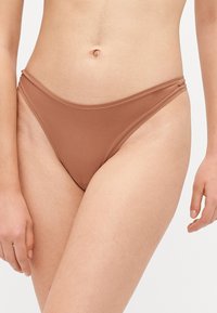 Bruine bikinionderkant van een gladde, rekbare stof. Heeft een low-rise ontwerp en smalle zijkruisjes. Naadloze afwerking en minimale bedekking.