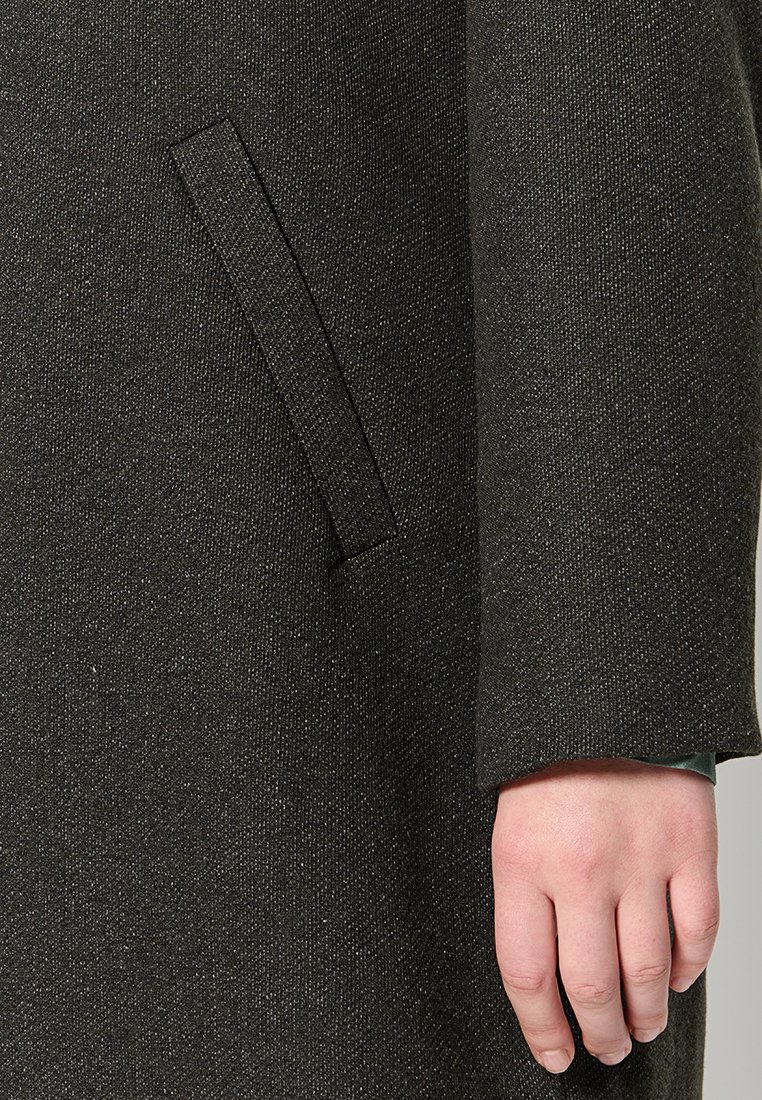 Manteau texturé gris foncé avec une poche latérale, de subtils éclats et une finition soignée au niveau des poignets. Tissu lisse et structuré.