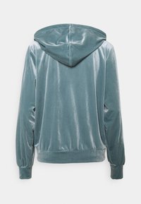 Huvtröja i teal, tillverkad av mjukt, glänsande tyg. Har långa ärmar och en avslappnad passform med mudd vid handlederna och nederkanten.