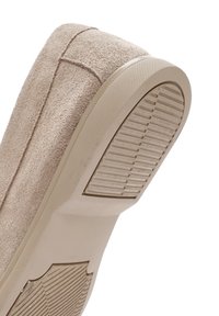 Beige suede shoe featuring a textured, rubber outsole with horizontal ridges and a rounded heel. Visible seam details on the upper.