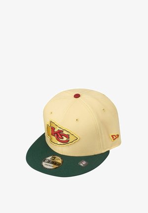 Cremfarbener Snapback-Cap mit grünem Schirm, auf der Vorderseite mit einem gestickten roten und gelben Kansas City-Logo und einem Größenetikett am Schirm.