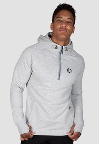Felpa grigia con cappuccio, chiusura a mezza zip, tasche laterali e logo nero. Presenta un tessuto testurizzato e un cappuccio con cordino regolabile.