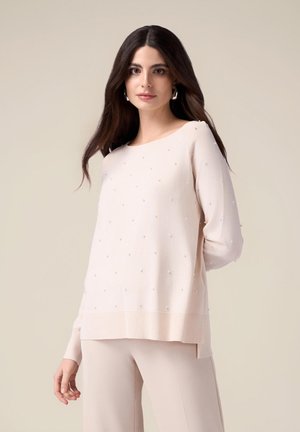 Maglione rosa chiaro con scollo rotondo, maniche lunghe e vestibilità ampia. Presenta dettagli a rilievo simili a perle e orlo a coste, texture liscia.