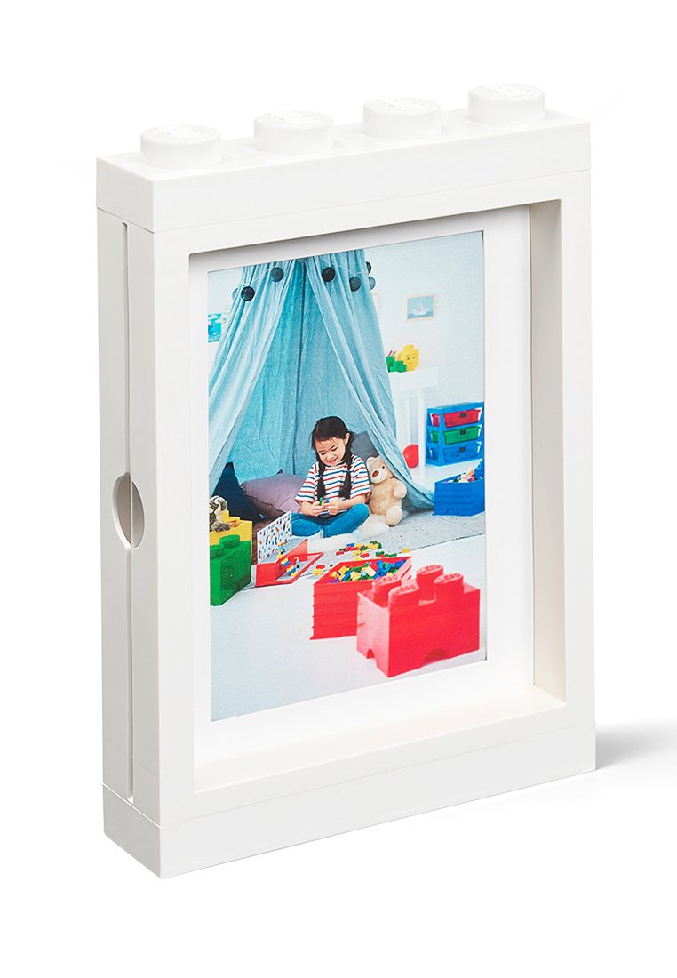 Biała ramka na zdjęcia w stylu LEGO z zaokrąglonym wierzchem, z kolorowym obrazem dziecka bawiącego się zabawkami w niebieskim namiocie.