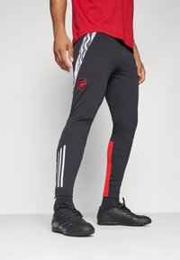 Leggings atléticos negros con acentos rojos y franjas blancas, con el logo del Arsenal. Fabricados con un tejido elástico para mayor comodidad y movilidad.