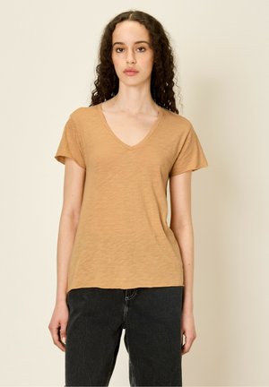 T-shirt à col en V, à manches courtes, de couleur brun clair, fabriqué en tissu doux et léger avec une coupe décontractée.
