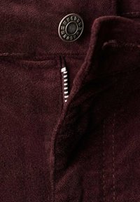 Tessuto borgogna con una texture liscia, caratterizzato da un bottone in metallo e una zip con dettagli di cucitura bianca lungo la cucitura.