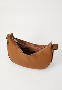 Sac à main en cuir marron avec une forme courbée, fermeture zippée et texture lisse. Intérieur spacieux avec un seul compartiment et une courte anse.