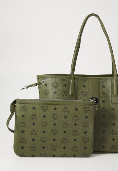Olive green textured leather tote bag and matching small zip pouch with black MCM logos and diamond patterns.