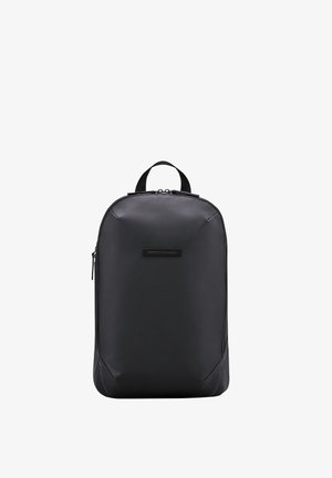 Sac à dos noir fabriqué à partir d'un matériau durable, avec une texture lisse, une forme arrondie, une poignée supérieure et une poche zippée à l'avant.