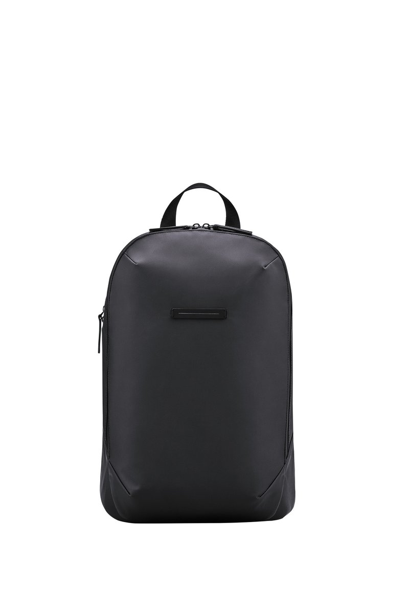 Sac à dos noir fabriqué à partir d'un matériau durable, avec une texture lisse, une forme arrondie, une poignée supérieure et une poche zippée à l'avant.