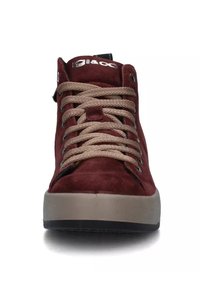 Sneaker alta in suede bordeaux, con lacci beige e occhielli in metallo. Suola in gomma spessa con fondo nero testurizzato per una buona aderenza.