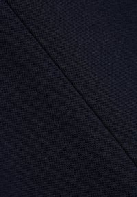 Tmavě modrá texturovaná tkanina se vzorem tkaní, obsahující diagonální šev. Materiál se jeví jako robustní a pevně tkaný.