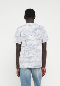 Γκρι μπλουζάκι με σχέδιο σε μικρό ύφος, κοντά μανίκια, που συνδυάζει ανοιχτές και σκοτεινές αποχρώσεις, με κλασικό στρογγυλό λαιμό.