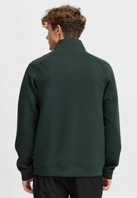 Dark green fleece sweatshirt with a high collar, long sleeves, and ribbed hem. Smooth texture, minimal stitching details visible.