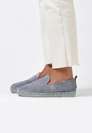 Espadrillas in suede grigio con design slip-on, suola intermedia in juta intrecciata e un logo sottile sul tallone. Abbinato a pantaloni bianchi sfrangiati.