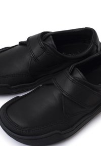 Zwarte schoenen van leer met een gladde textuur en een versterkte neus. Voorzien van een klittenbandsluiting en een geëxtraheerde rubberen zool voor grip.