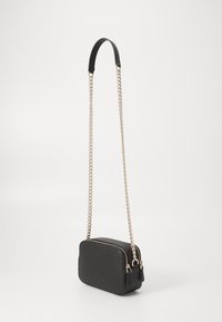 Mustmust ristcrossbody kott, millel on tekstureeritud pind, topelt tõmblukud ja pikk hõbedane kett, ning sile must ülemine käepide.