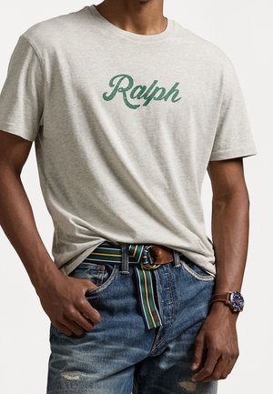 Szary t-shirt z dzianiny typu heather z okrągłym dekoltem, ozdobiony zielonym, kursywowym napisem "Ralph", zestawiony z niebieskimi, postarzanymi dżinsami oraz paskiem w wielokolorowe paski.