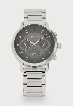 Montre en acier inoxydable argenté avec un cadran texturé gris foncé, trois sous-cadrans et un bracelet en maillons métalliques. Les caractéristiques incluent des indications de date et de jour.