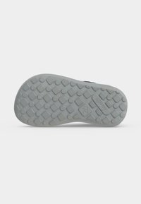 Semelle d’une chaussure enfant avec des motifs de bande de roulement circulaires et carrés en relief, taille 27 indiquée près de la zone du talon.